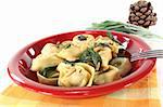 stuffed tortellini with sage butter and pine nuts on a light background