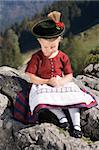 Little blonde girl in typical Bavarian costume on the mountain and pray