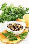 marinated mussels with flat leaf parsley in a bowl on checked napkin