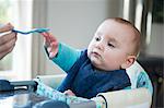 Baby reaching for spoon at table