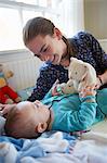 Girl playing with baby brother on bed