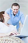 Couple using laptop in armchair