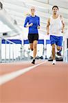 Couple en cours d'exécution sur une piste intérieure dans une salle de sport