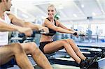 Couple using rowing machines in gym