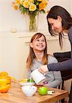 Woman pouring milk for daughter at table