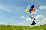 Boy playing with balloons in meadow