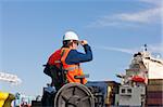 Transportation engineer in a wheelchair inspecting shipping containers at shipping port