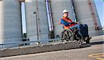 Facilities engineer in wheelchair inspecting outdoor bulk storage tanks