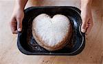 Person holding a tray with heart shaped cake