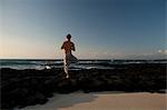 Homme avec yoga scène torse nu se posent sur la coulée de lave de l'océan sur la grande île d'Hawaï