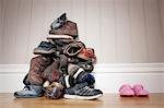 Large pile of boy's shoes beside one pair of girl's shoes