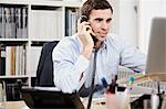 Young man on telephone and working on laptop