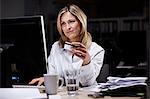 Businesswoman in dark office, using credit card online