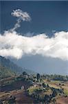 Dorf von Shingyer gegen eine dramatische Kulisse der Berge und Wolken, Phobjikha Tal, Bhutan, Himalaya, Asien