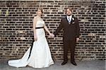 Bride and Groom Standing in front of Brick Wall