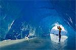 Man photographs inside an ice cave of an iceberg frozen in Mendenhall Lake, Juneau, Southeast Alaska, Winter