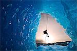 COMPOSITE : Vue depuis l'intérieur d'une grotte de glace d'iceberg congelé comme un grimpeur de glace du lac Mendenhall rappels descendre une corde, Juneau, sud-est de l'Alaska, hiver