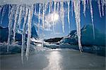 Sun shines through icicles hanging from the edge of an iceberg frozen into the surface of Mendenhall Lake near the terminus of Mendenhall Glacier, Juneau, Southeast Alaska, Winter