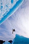 Ein Eiskletterer schwingt unten aus Seil erreichen Gesicht eines großen Eisbergs gefroren in Juneau, Alaska Southeast, Mendenhall Lake, Winter