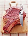 Raw rib of beef on chopping board with knife