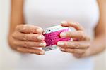 Woman's hand holding birth control pills, cropped