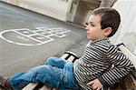 Boy sitting on bench, looking sad