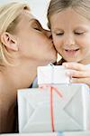 Mère embrassant les joues de la jeune fille en fille se penche sur les cadeaux emballés