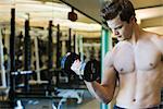 Barechested young man lifting dumbbell