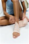 Woman bandaging foot and ankle, cropped