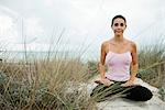 Mature woman sitting in lotus position on beach, portrait