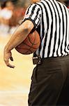 Basketball referee holding basketball, rear view
