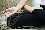 Woman sitting in lotus position, fingers in meditation position, cropped