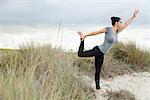 Reife Frau in Natarajasana-Pose am Strand, Seitenansicht