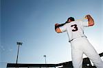 Baseball player holding bat, rear view