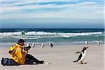 A visitor to Saunders Island photographs Gentoo Penguins on the sandy beach.  The first British garrison on the Falklands Islands was built on Saunders Island in 1765.