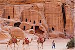 Kamele und Pferde Reiten vorbei an den Gräbern und Fassaden von The Outer Siq, Petra, Jordanien