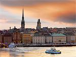 Suède, Stockholm, Riddarfjarden, Gamla Stan ; traversiers à passagers dans la baie au crépuscule.