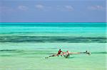 Tanzania, Zanzibar, Unguja, Jambiani. A man sits on his boat near the shore.