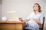 Pregnant woman using laptop in kitchen