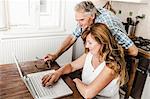 Older couple using laptop in kitchen