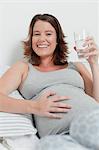 Woman holding pregnant belly on bed