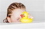 Girl playing with rubber duck in bath