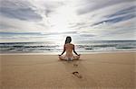 Femme méditant sur la plage de sable