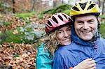 Portrait de couple d'âge mûr portant des casques de vélo dans la forêt