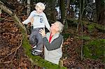 Grandfather holding boy on tree branch