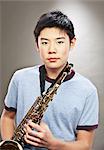 Portrait of young Asian teenage boy holding saxophone