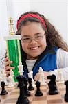 Portrait of young girl holding chess trophy