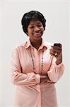 Femme mature afro-américaine à l'aide de téléphone portable, studio shot