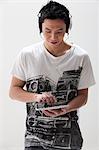 Young Asian man using digital tablet with headphones, studio shot