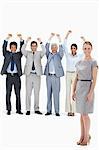 Multicultural business team raising their arms with a smiling woman in foreground against white background